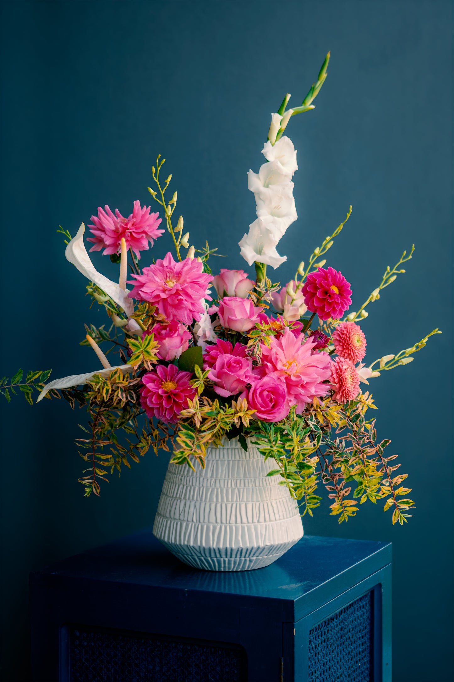 Floral arrangement in a white vase against a dark blue background